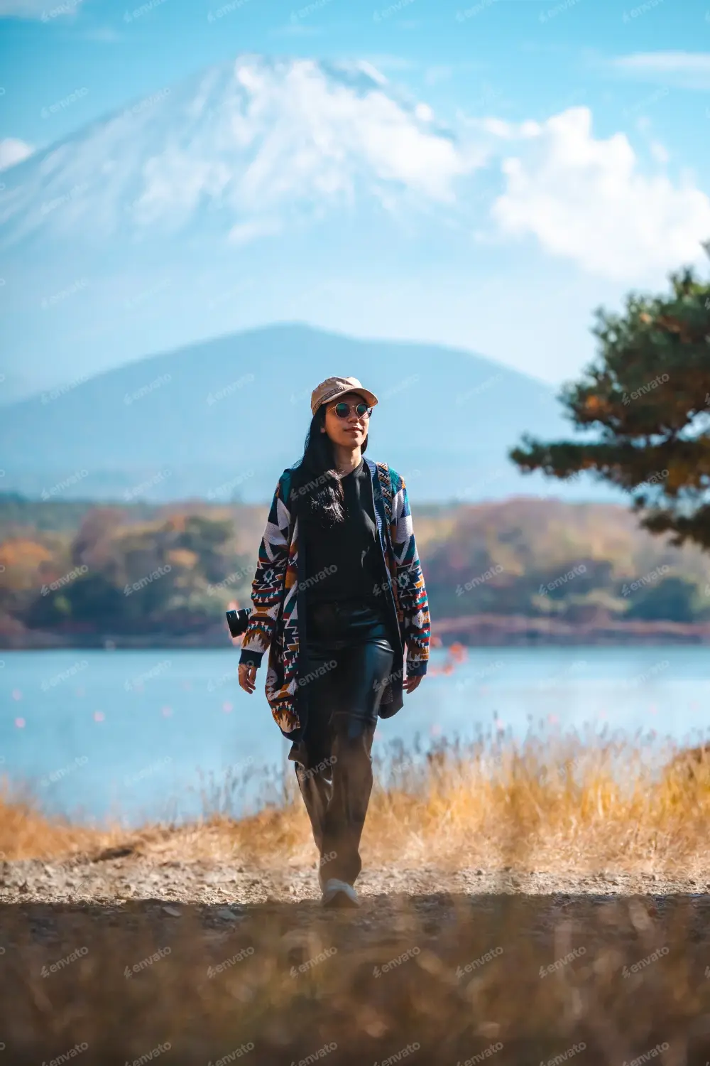 A person stands in the mountains, holding a guitar